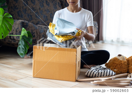 Woman holding Clothes with Donate Box In her room, Donation Concept. 59002603