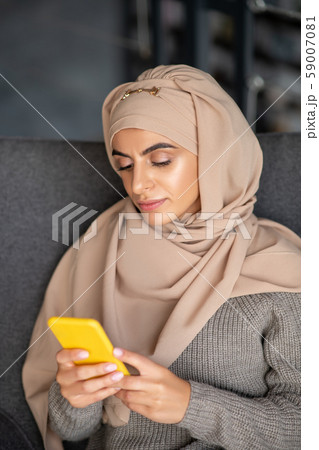 Young Muslim girl using phone searching some information in the Internet Young Muslim girl using phone searching some information in the Internet 59007081