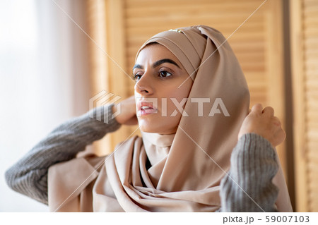 Pretty Muslim girl dressing up in hijab in bedroom 59007103