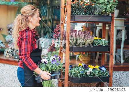Young beautiful florist posing, smiling among plants. Young beautiful florist posing, smiling among plants. 59008198