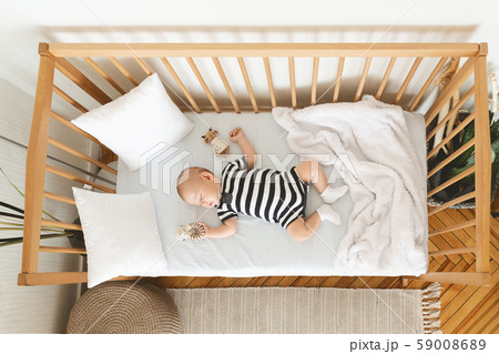 Adorable baby sleeping in crib with toy in his hand 59008689