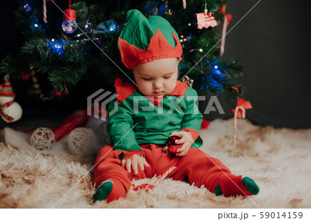 baby boy in elf costume sitting under Christmas tree baby boy in elf costume sitting under Christmas tree 59014159