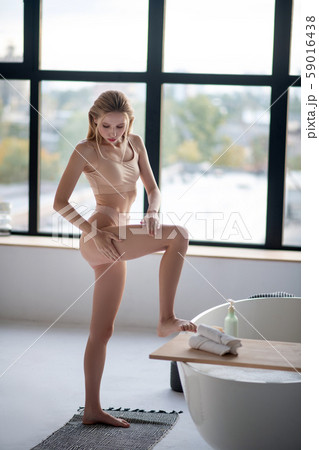 Skinny young woman nourishing her legs with cream Skinny young woman nourishing her legs with cream 59016438