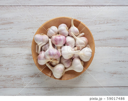 Garlic in a wooden bowl on a white wooden table.  59017486