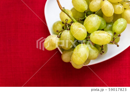 Big tasty sweet grapes on a white plate on a red Big tasty sweet grapes on a white plate on a red 59017823