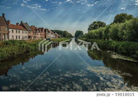 Houses and grove along canal with sky reflected on water Houses and grove along canal with sky reflected on water 59018015