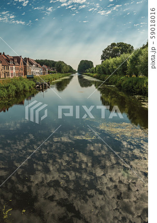 Houses and grove along canal with sky reflected on water Houses and grove along canal with sky reflected on water 59018016