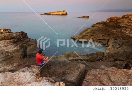 the guy on the edge of the cliff looks into the distance 59018936