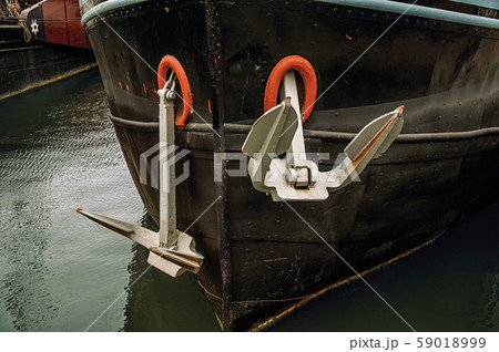 Prow and rusty anchor of a boat moored in port 59018999