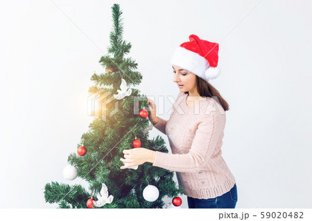 Holidays concept - Girl in santa hat decorated christmas tree. Waiting for christmas. 59020482