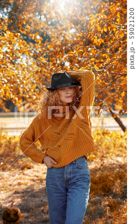 Young adult mother and daughter looking at carved pumpkin with smoke 59021200