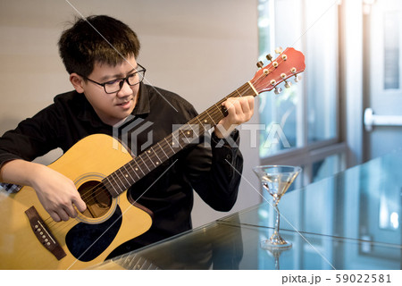 Asian man playing acoustic guitar at bar counter 59022581
