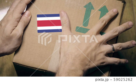 Warehouse worker places sticker with flag of Costa Rica on the box. Costa Rican import or export 59025262