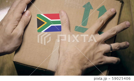 Warehouse worker places sticker with flag of South Africa on the box. South African import or export Warehouse worker places sticker with flag of South Africa on the box. South African import or export 59025406