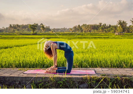 Young woman practice yoga outdoor in rice fields in the morning during wellness retreat in Bali 59034741