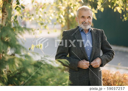 Portrait of happy elderly man in the park. Gray-haired bearded man in gray jacket 59037257