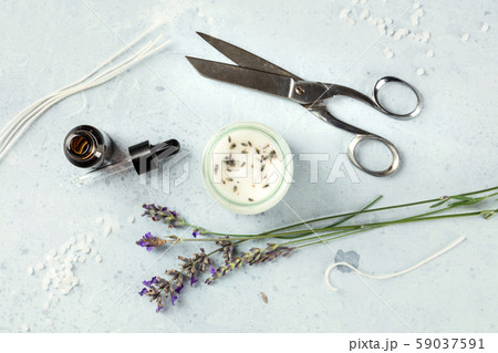 Handmade lavender scented candle with essential oil, flowers, wax, wicks, and scissors, flat lay 59037591