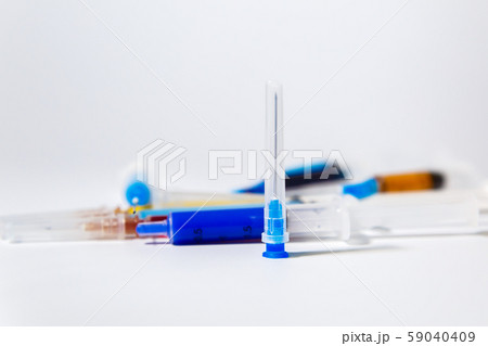 Medical needle on the background of a set of medical syringes with colored liquids inside. 59040409