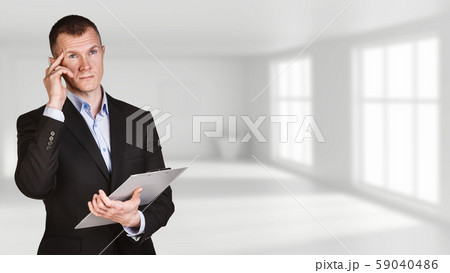 Thoughtful businessman posing in white office background. 59040486