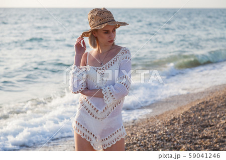 portrait of a fashionable woman in a dress and hat on the beach of the sea 59041246