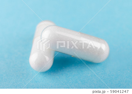 two white capsules of nutritional supplement msm, sulfur on blue background two white capsules of nutritional supplement msm, sulfur on blue background 59041247