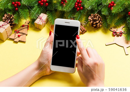 Top view of phone in female hand on festive yellow Top view of phone in female hand on festive yellow 59041636