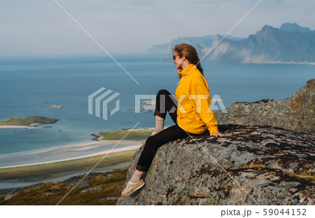 Girl in yellow jacket stitting on stone  59044152