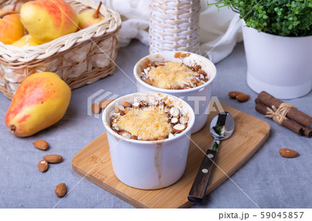 Crumble with caramelized pear, cinnamon and almonds in a white ramekin. Close-up. 59045857