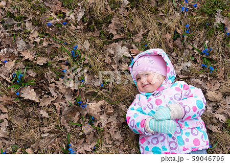 Little smiling girl lying down in the field of snowdrop flowers 59046796