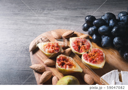 Still life cheese plate on a wooden cutting board lies sliced cheese with mold almonds in the shell Still life cheese plate on a wooden cutting board lies sliced cheese with mold almonds in the shell 59047082