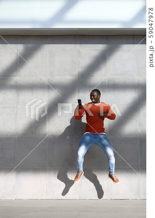African Man Jumping For Joy Holding Phone African Man Jumping For Joy Holding Phone 59047978