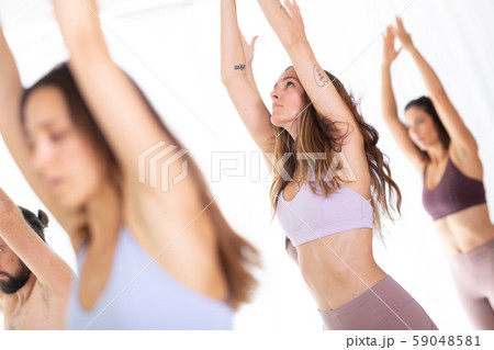 Group of young sporty attractive women in yoga studio, practicing yoga lesson with instructor 59048581