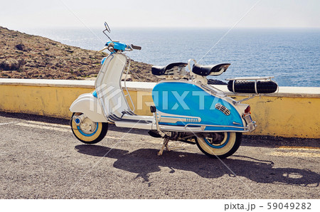 Vintage blue-white two-seater scooter parked on 59049282