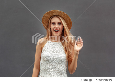 Freestyle. Young woman in hat standing isolated on wall waving to camera surprised 59049649