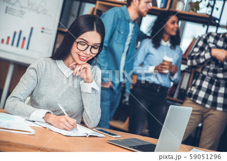 Startupers working together at office woman in eyeglasses sitting at table taking notes in organizer 59051296