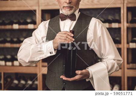 Sommelier Concept. Senior man standing with botle of wine confident close-up Sommelier Concept. Senior man standing with botle of wine confident close-up 59051771