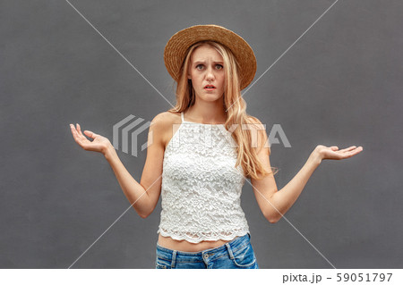 Freestyle. Young woman in hat standing isolated on wall hands aside confused 59051797