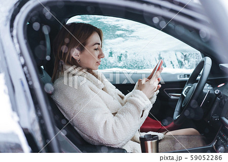 Attractive woman driver nsitting behind the steering wheel in her car Attractive woman driver nsitting behind the steering wheel in her car 59052286