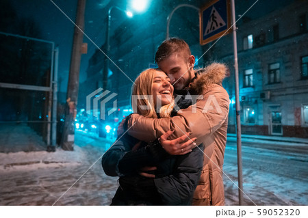Young adult couple walking on snow covered sidewalk Young adult couple walking on snow covered sidewalk 59052320