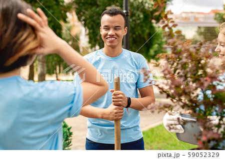 Volunteering. Young people volunteers standing outdoors boy close-up with shovel smiling cheerful 59052329