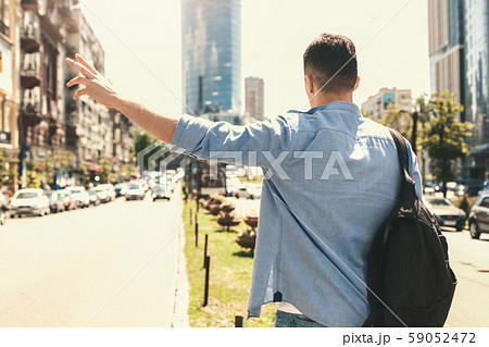 Outdoors Leisure. Stylish guy traveler standing near road hitchhiking back view Outdoors Leisure. Stylish guy traveler standing near road hitchhiking back view 59052472