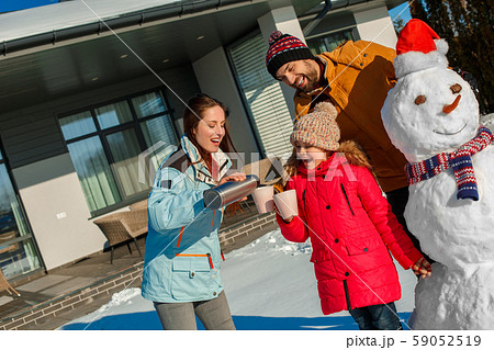 Winter vacation. Family time together outdoors standing drinking hot tea smiling cheerful Winter vacation. Family time together outdoors standing drinking hot tea smiling cheerful 59052519