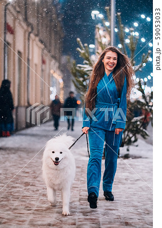 Woman walking down with white dog by alley. Woman walking down with white dog by alley. 59053033