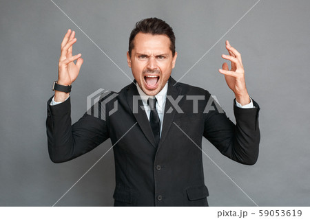 Businessman studio standing isolated on grey shouting furious at camera 59053619