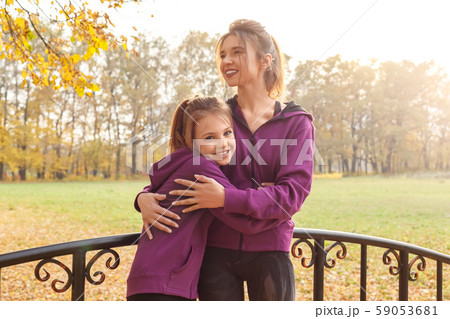Outdoors leisure. Sisters standing hugging in the autumn park on the bridge laughing happy 59053681
