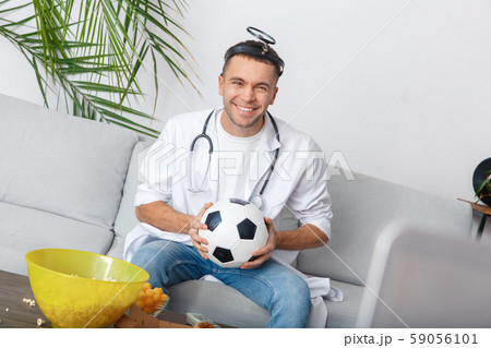 Young man sport fan watching match looking camera smiling Young man sport fan watching match looking camera smiling 59056101