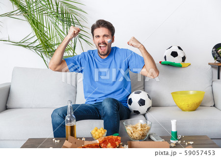 Young man sport fan watching match in a blue t-shirt cheering team Young man sport fan watching match in a blue t-shirt cheering team 59057453