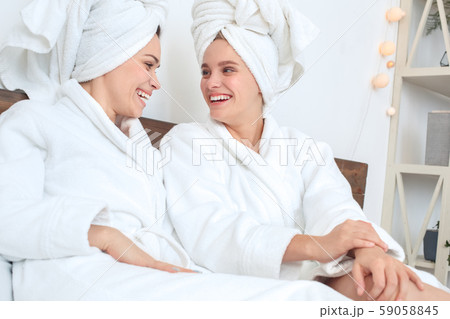Friends together at home in bath robes beauty care sitting laughing at joke close-up 59058845