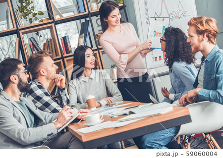 Startupers working together at office sitting smiling looking at pregnant woman standing showing 59060004