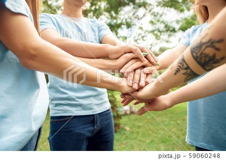 Volunteering. Young people volunteers outdoors standing hands together side view close-up 59060248
